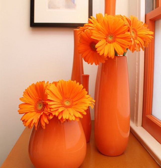 Яркие вазы апельсинового оттенка с оранжевыми цветами выступают в качестве сильного цветового акцента 