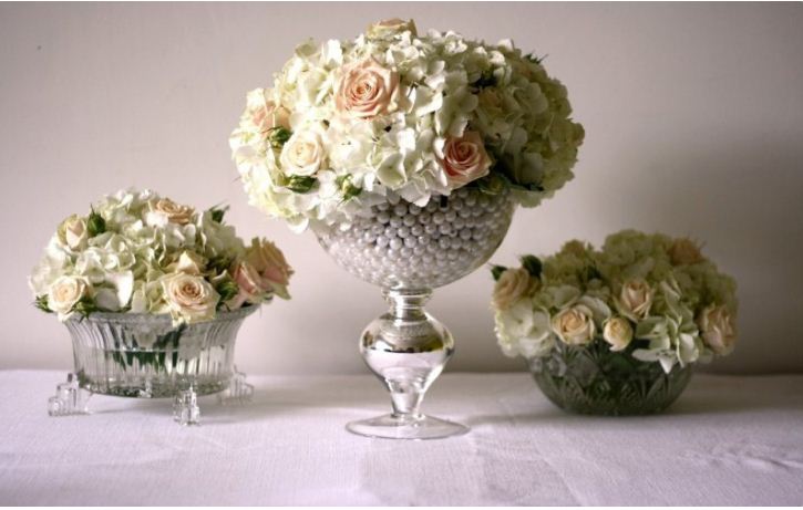 Композиции из цветков двух пастельных оттенков в хрустальных низких вазах.